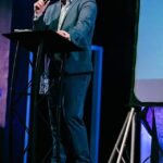 Man speaking at podium on stage
