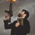 Rifle firing with visible muzzle flash beside Bible